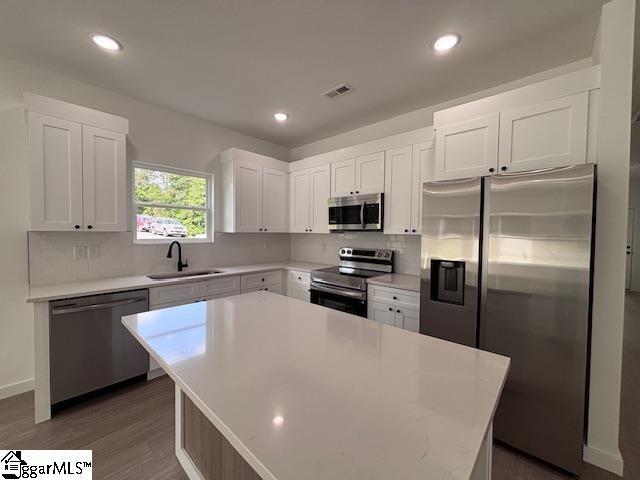 kitchen with a sink, light countertops, stainless steel appliances, white cabinetry, and tasteful backsplash