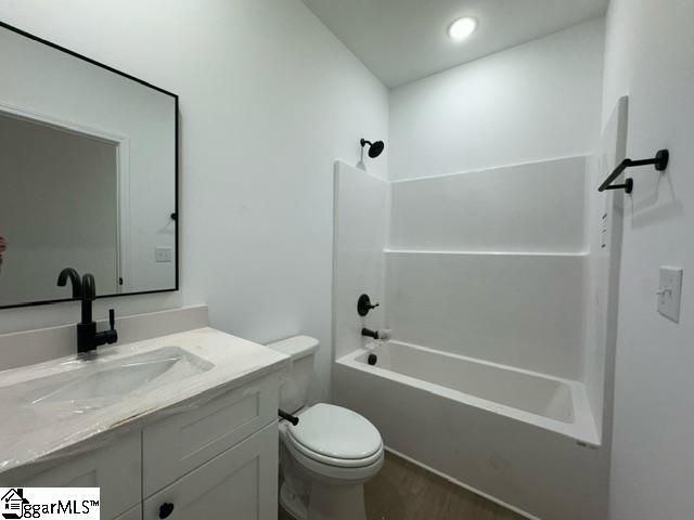 bathroom featuring toilet,  shower combination, wood finished floors, and vanity