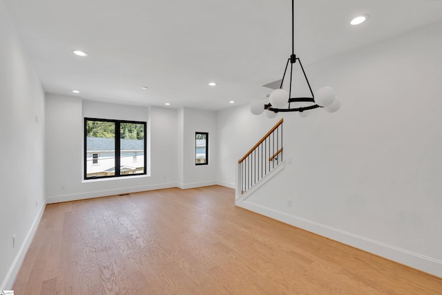 empty room featuring light wood-style floors, stairway, and baseboards