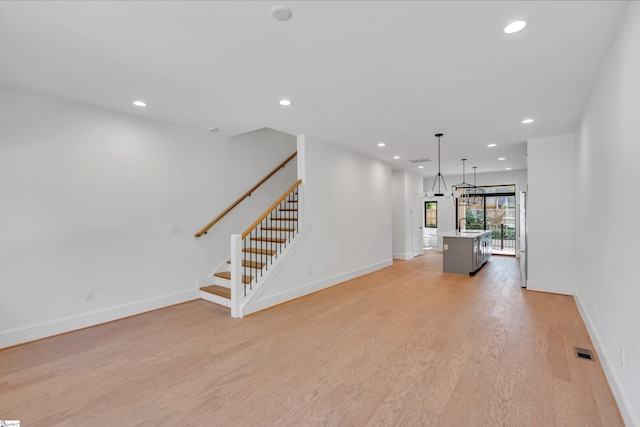 unfurnished living room with stairs, light wood finished floors, visible vents, and recessed lighting