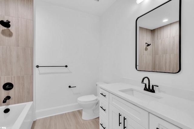 bathroom with toilet, wood finished floors, vanity, baseboards, and tub / shower combination