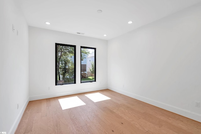 empty room with light wood-style floors, baseboards, visible vents, and recessed lighting