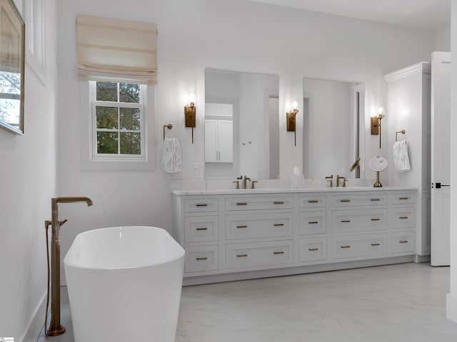 full bath featuring marble finish floor, a sink, a freestanding bath, and double vanity