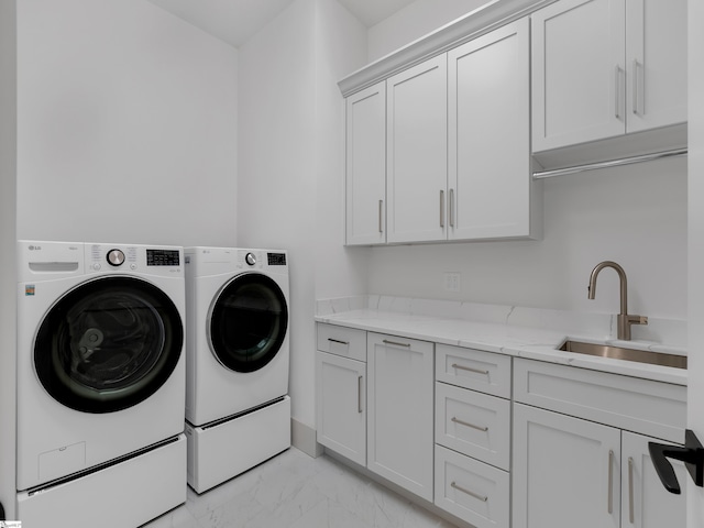 clothes washing area featuring marble finish floor, washing machine and clothes dryer, a sink, and cabinet space