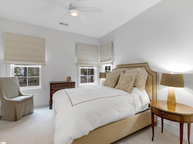 carpeted bedroom featuring multiple windows, visible vents, and a ceiling fan