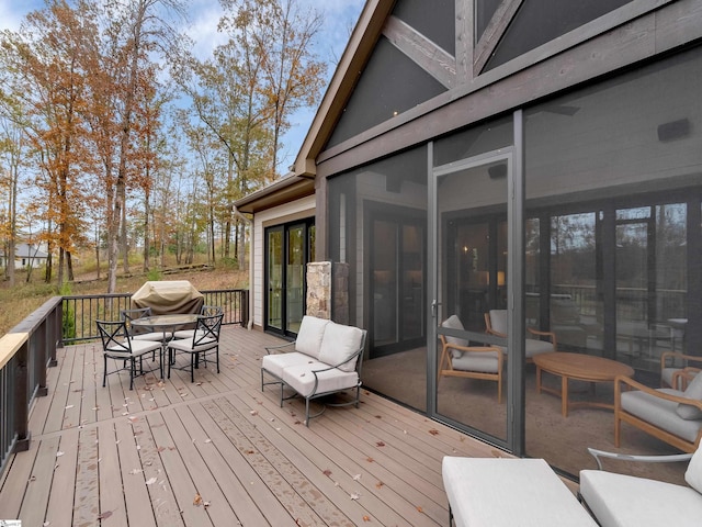 wooden deck with a sunroom and outdoor dining area