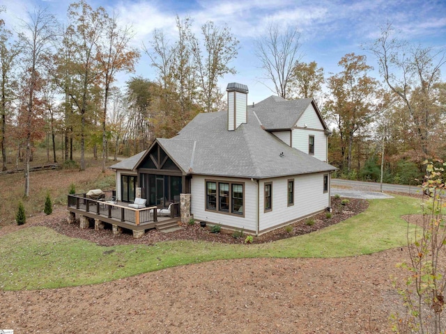 back of house featuring a shingled roof, a lawn, a chimney, and a wooden deck