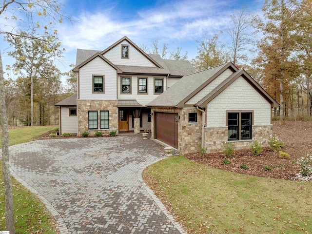 view of front facade featuring decorative driveway, a shingled roof, a front yard, a garage, and stone siding