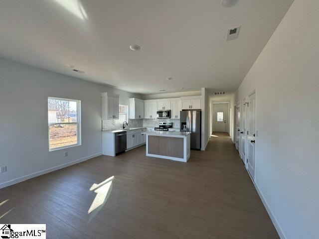 kitchen featuring white cabinets, dark wood-style floors, appliances with stainless steel finishes, and light countertops