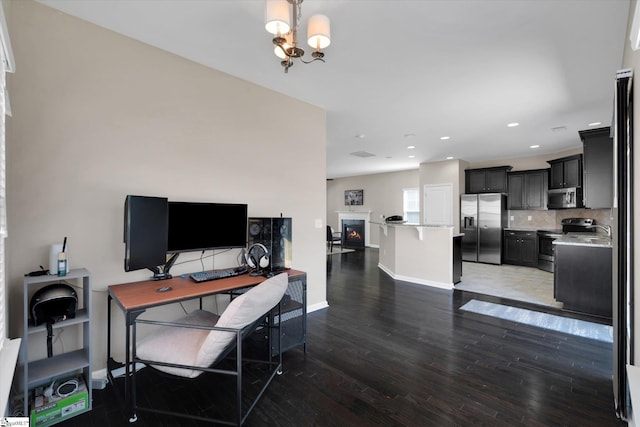 office with baseboards, light wood-style flooring, a lit fireplace, a chandelier, and recessed lighting