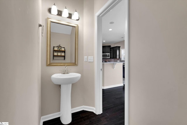 bathroom featuring a sink, baseboards, wood finished floors, and recessed lighting