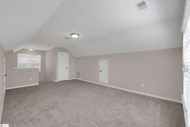 additional living space featuring carpet floors, visible vents, and vaulted ceiling