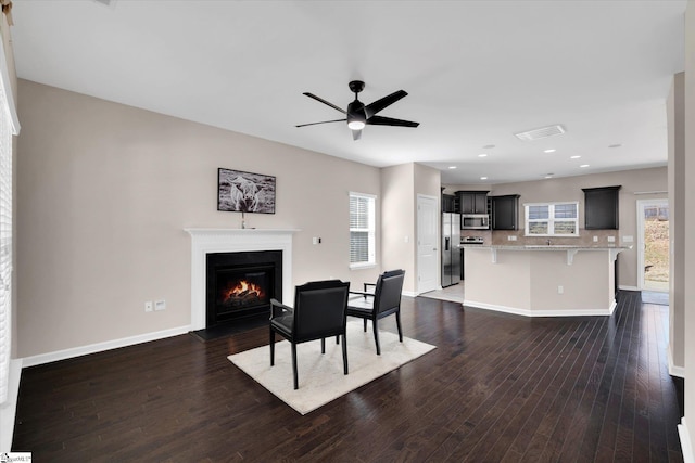 dining area with a warm lit fireplace, plenty of natural light, baseboards, and dark wood-style flooring