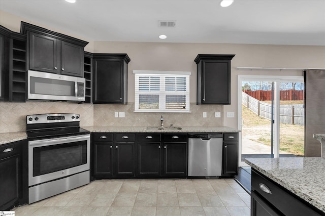 kitchen featuring visible vents, dark cabinets, stainless steel appliances, open shelves, and a sink