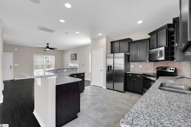 kitchen with a kitchen island with sink, stainless steel appliances, a sink, visible vents, and tasteful backsplash