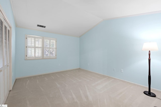 unfurnished bedroom featuring crown molding, lofted ceiling, a closet, visible vents, and carpet flooring