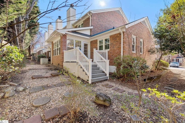 view of front of home featuring crawl space, brick siding, and a chimney