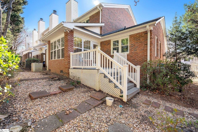 back of property featuring brick siding and a chimney