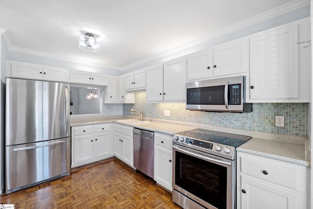 kitchen featuring light countertops, appliances with stainless steel finishes, ornamental molding, white cabinets, and a sink