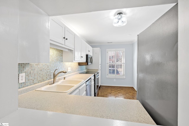 kitchen featuring decorative backsplash, appliances with stainless steel finishes, light countertops, white cabinetry, and a sink