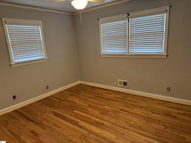 spare room with visible vents, ornamental molding, baseboards, and wood finished floors