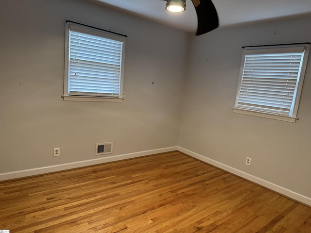 empty room with visible vents, light wood-type flooring, and baseboards