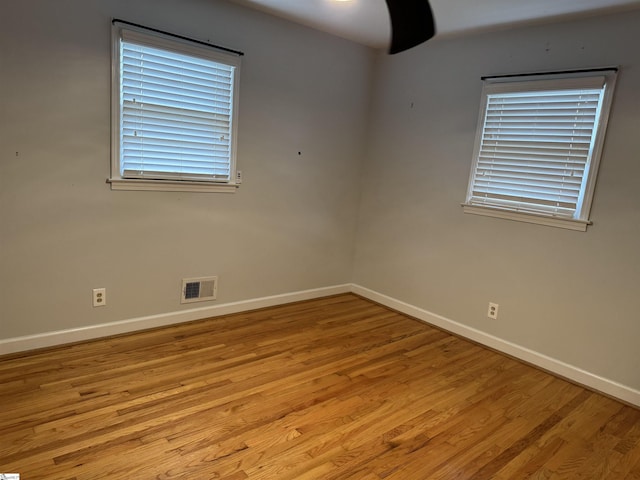 empty room featuring visible vents, baseboards, and wood finished floors