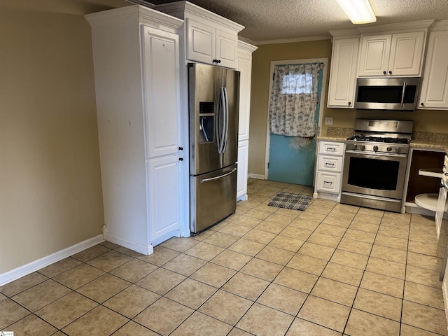 kitchen featuring ornamental molding, light tile patterned floors, appliances with stainless steel finishes, and a textured ceiling