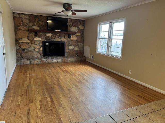 unfurnished living room with wood finished floors, a fireplace, ceiling fan, ornamental molding, and a textured ceiling