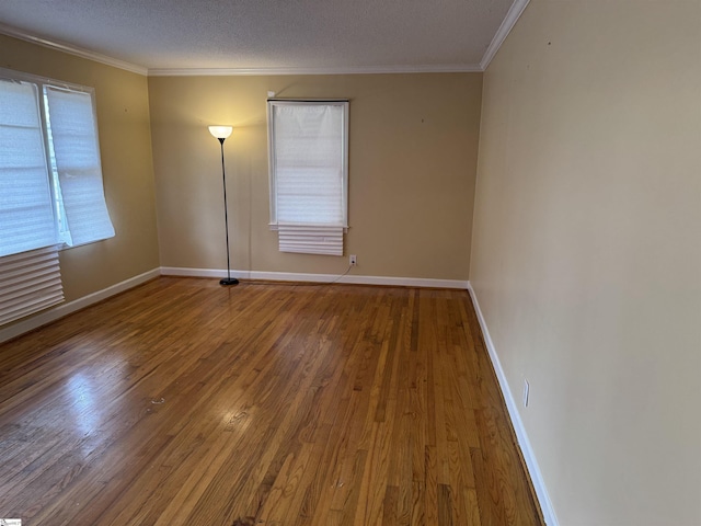 unfurnished room featuring a textured ceiling, crown molding, baseboards, and wood-type flooring