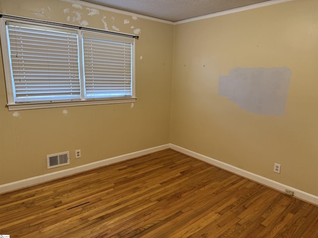 unfurnished room featuring baseboards, wood finished floors, visible vents, and a textured ceiling