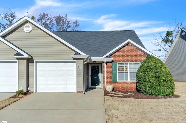 ranch-style home featuring an attached garage, brick siding, driveway, and roof with shingles