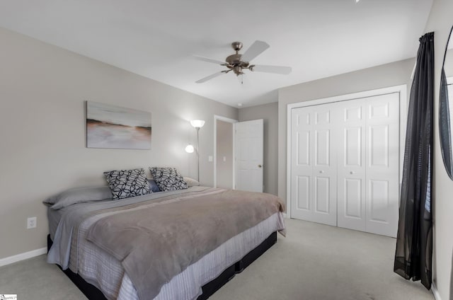 bedroom featuring a closet, baseboards, light colored carpet, and ceiling fan