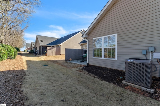 view of home's exterior with central air condition unit, a patio, and fence