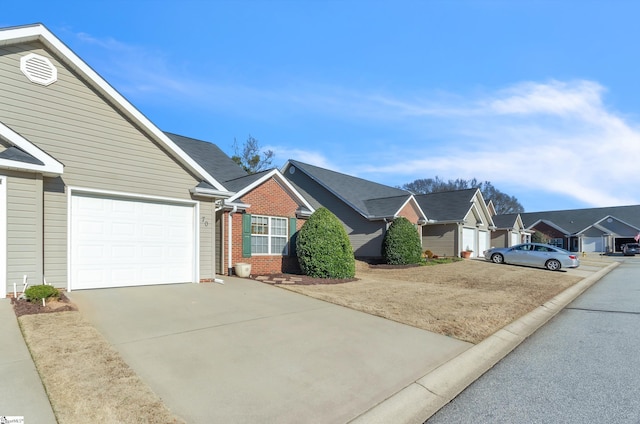 single story home featuring a garage, a residential view, brick siding, and driveway