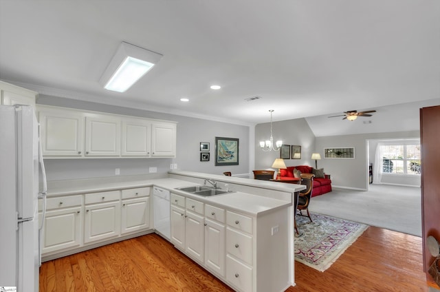 kitchen featuring open floor plan, light countertops, a peninsula, white appliances, and a sink