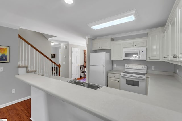 kitchen featuring white appliances, dark wood finished floors, a sink, white cabinetry, and crown molding