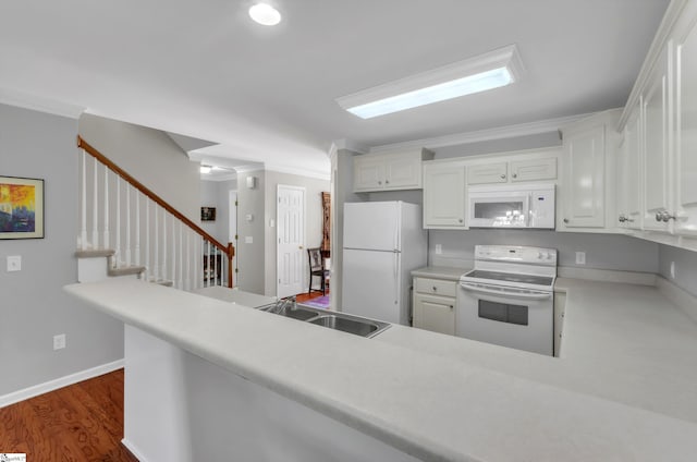 kitchen with ornamental molding, a sink, dark wood finished floors, white appliances, and white cabinets