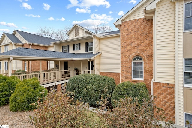 view of front of home featuring brick siding and a porch