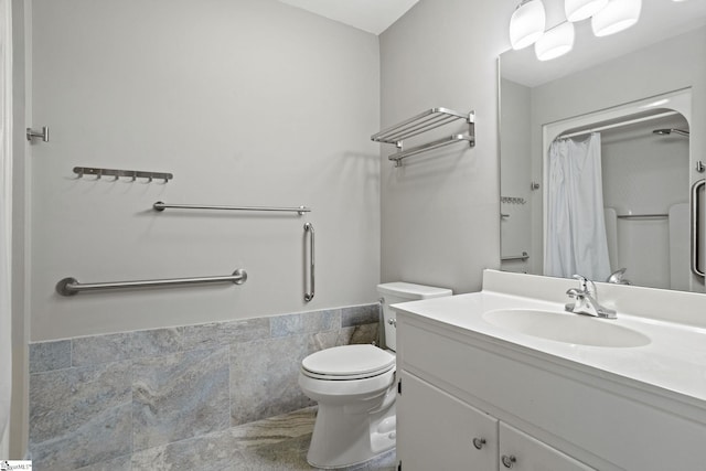 bathroom featuring vanity, a wainscoted wall, curtained shower, tile walls, and toilet