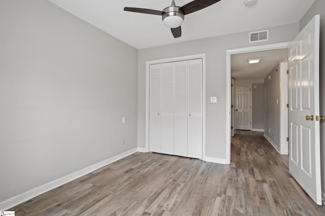 unfurnished bedroom with visible vents, ceiling fan, baseboards, wood finished floors, and a closet