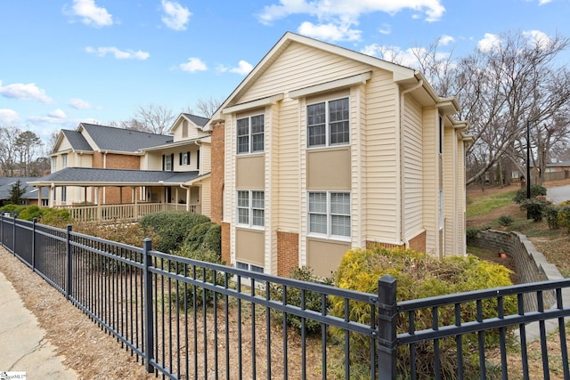 exterior space featuring a residential view, brick siding, and fence