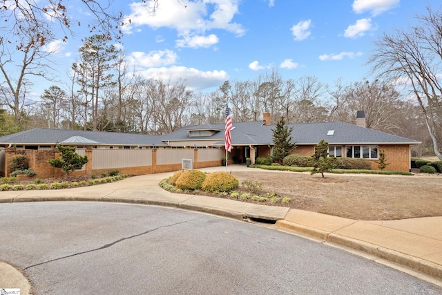 view of front of home with fence, a chimney, concrete driveway, a garage, and brick siding