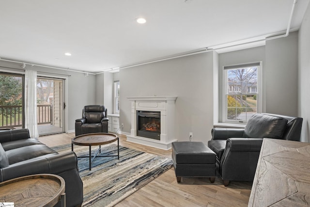 living area with light wood finished floors, recessed lighting, and a fireplace with raised hearth