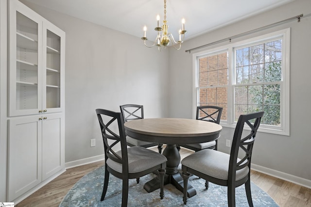 dining area featuring an inviting chandelier, baseboards, and light wood finished floors