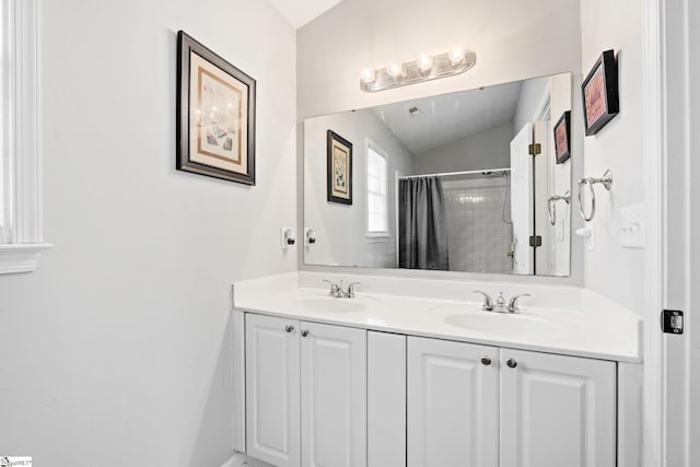 bathroom featuring double vanity, a shower with curtain, vaulted ceiling, and a sink