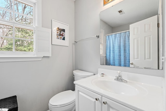 full bathroom with vanity, a shower with shower curtain, toilet, and visible vents