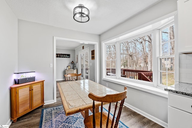 dining space with dark wood-style floors, baseboards, and a textured ceiling