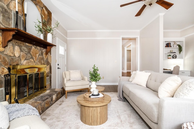 living area with built in shelves, wood finished floors, a fireplace, crown molding, and baseboards