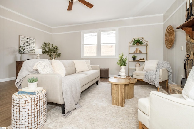 living area featuring light wood-type flooring, baseboards, ceiling fan, and crown molding